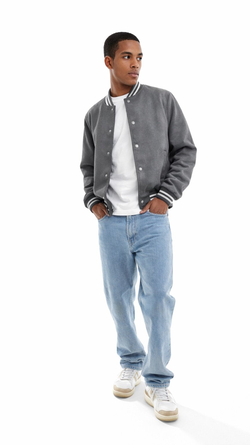 Man wearing a gray varsity jacket, white shirt, and light blue jeans on a white background