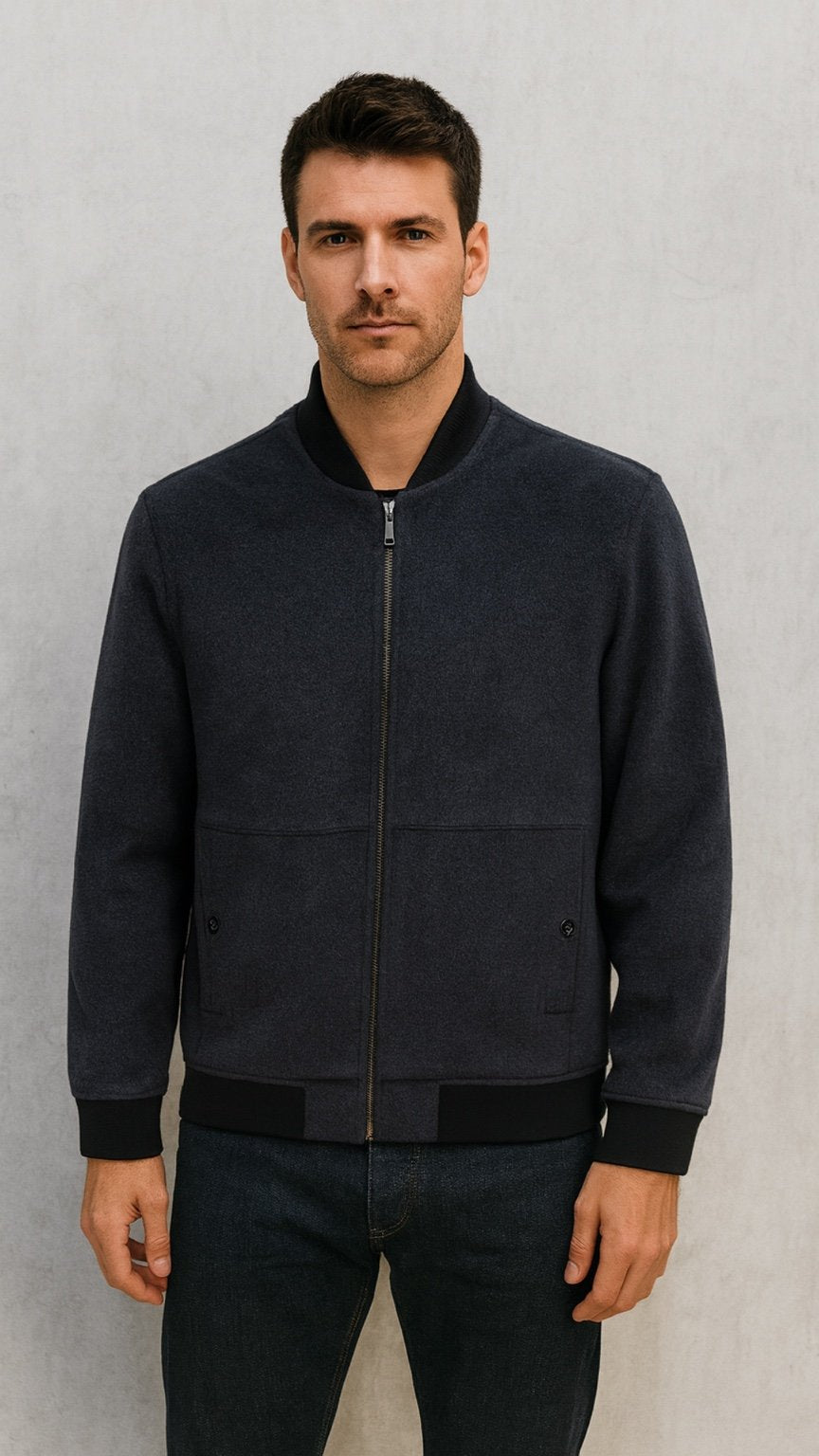 Man wearing a dark blue jacket against a gray background