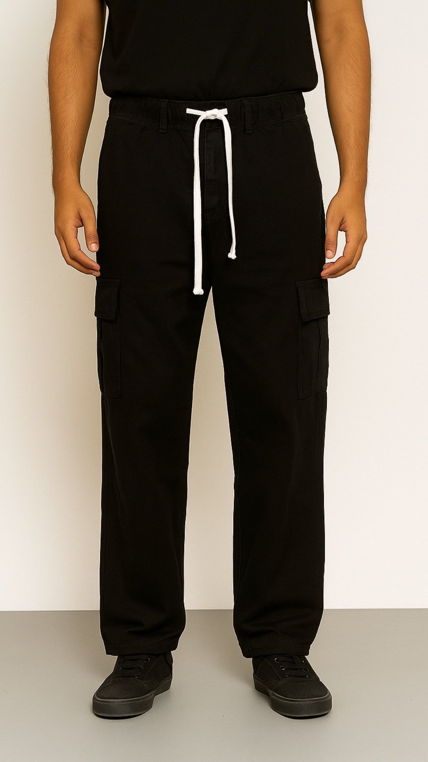 Person wearing black cargo pants with a white drawstring on a plain background