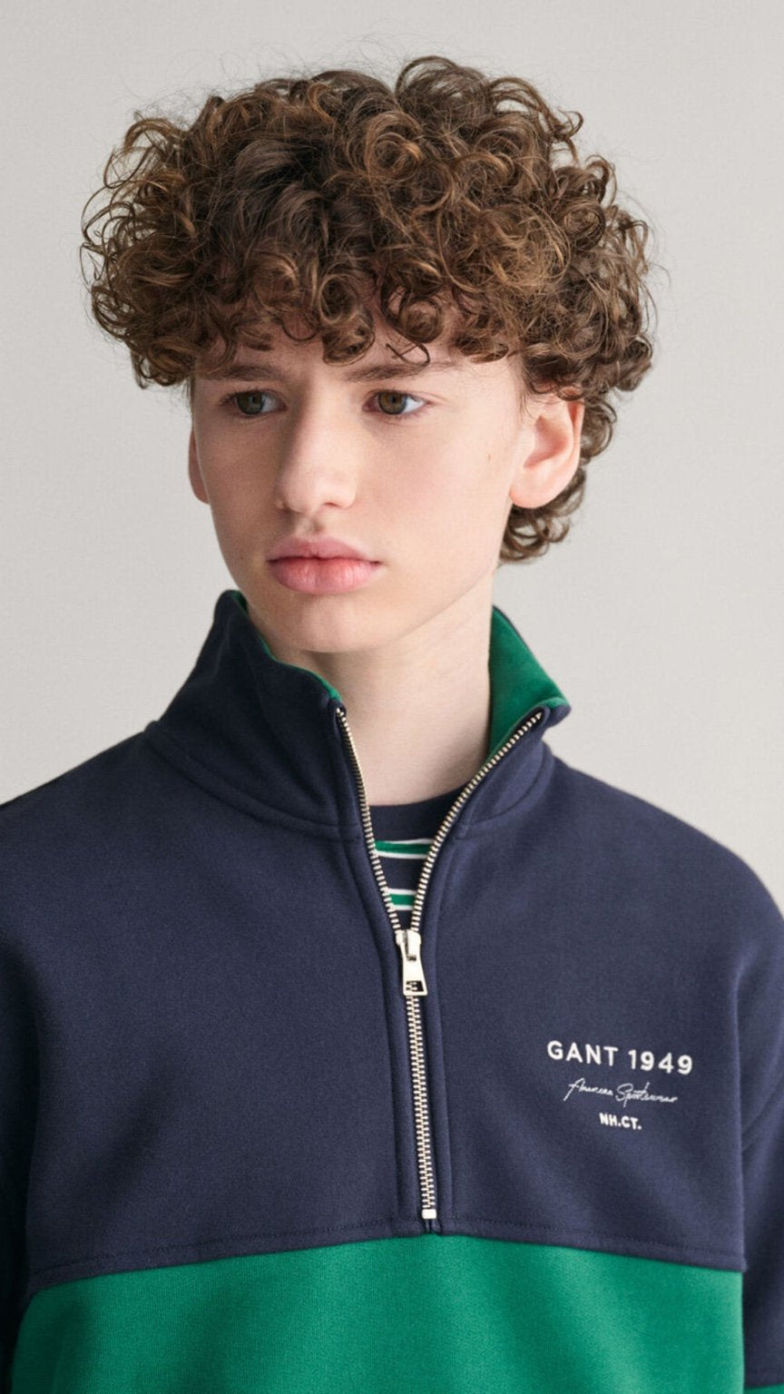 Person wearing a navy and green Gant jacket with a plain background