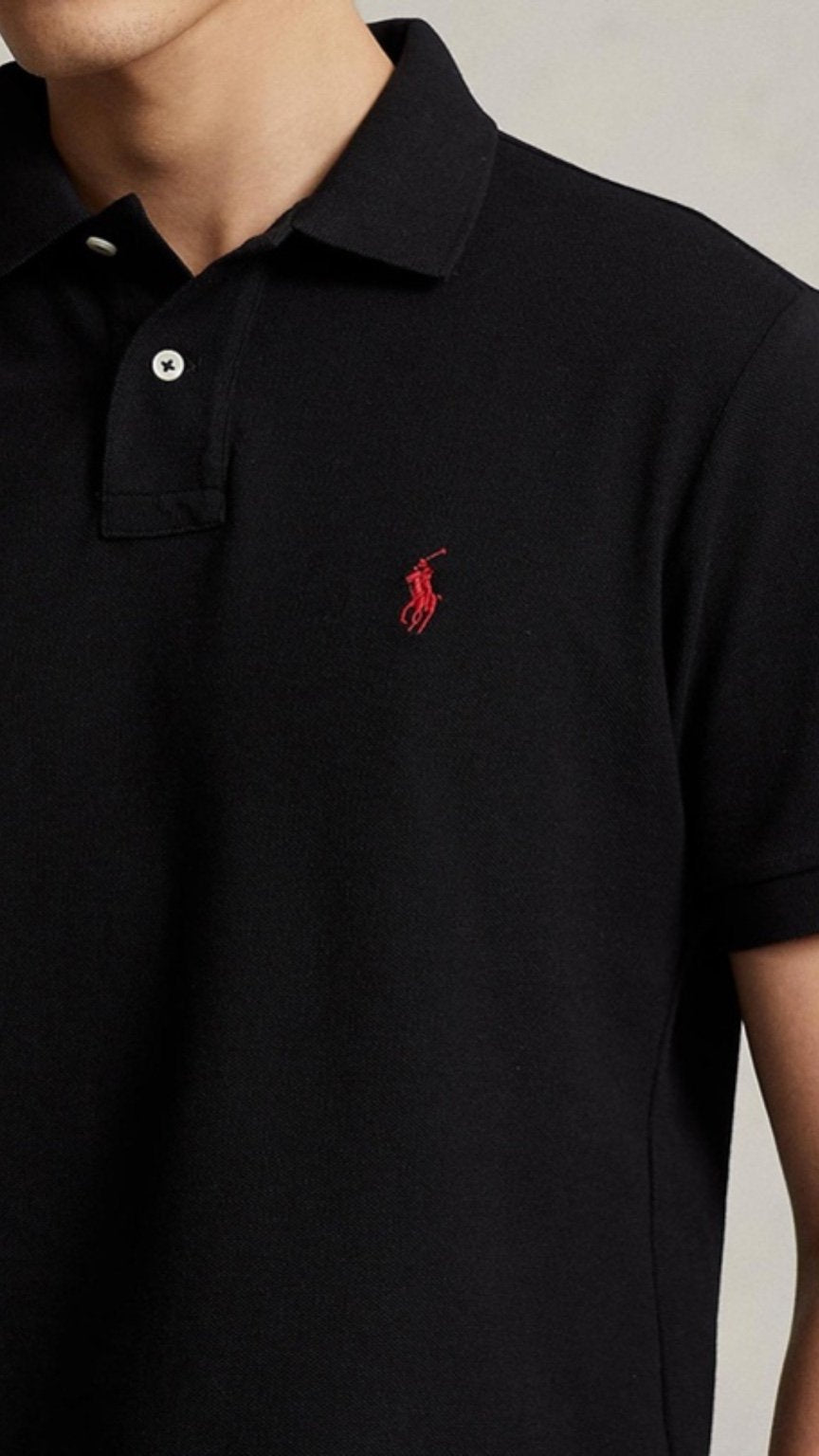 Black polo shirt with a red logo on a neutral background