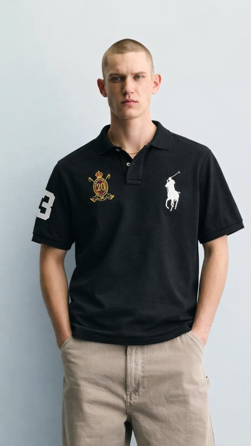 Man wearing a black Polo Ralph Lauren polo shirt with logos on a light gray background
