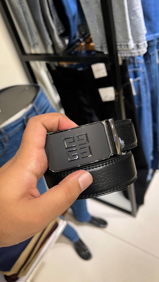 Hand holding a black belt with a brand logo in front of a clothing rack.