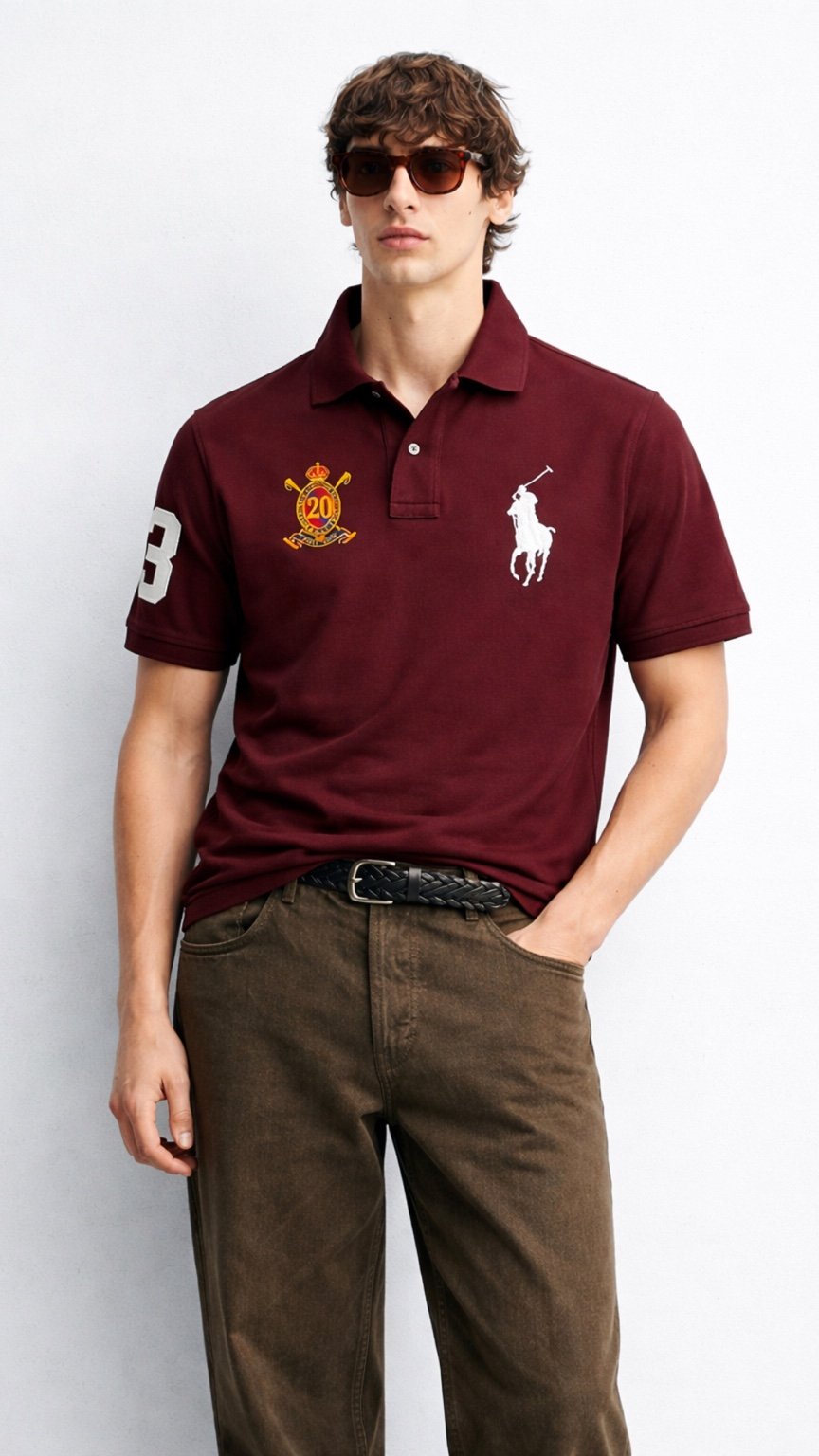 Man wearing a maroon polo shirt with logos, sunglasses, and brown pants on a white background