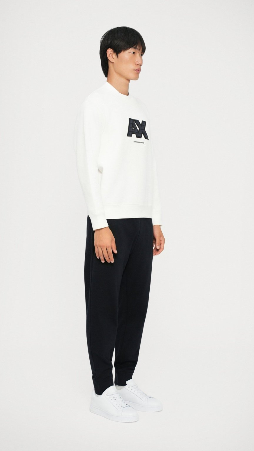 Person wearing a white sweatshirt with a logo and black pants on a white background