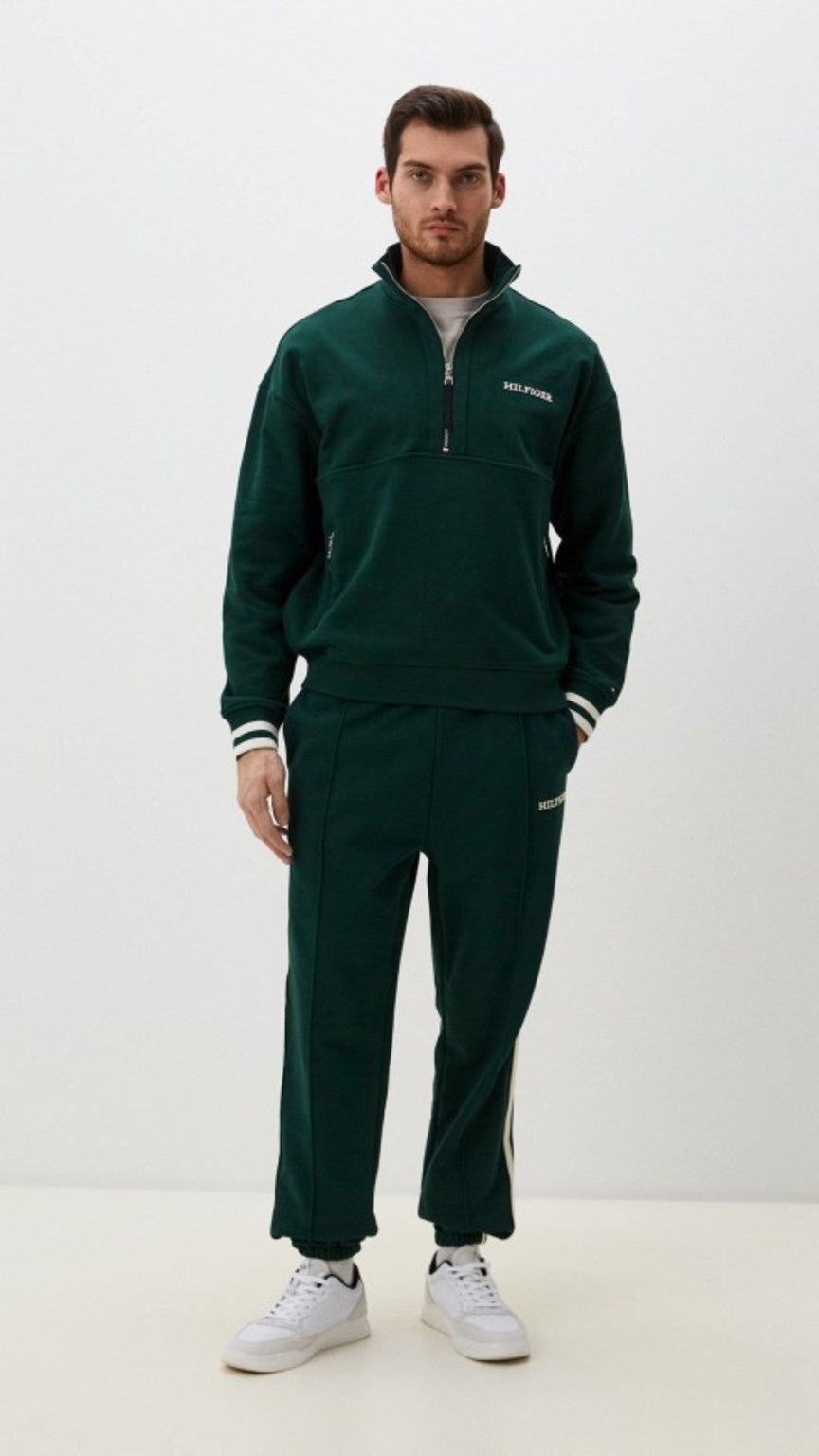 Man wearing a green tracksuit with a brand logo on a white background
