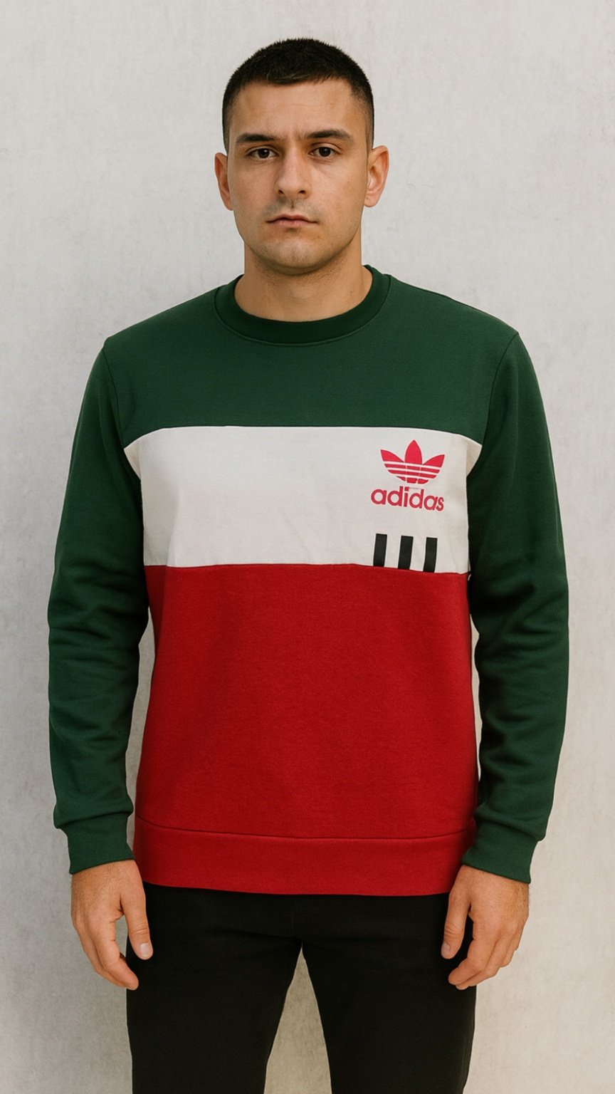 Person wearing a green, white, and red Adidas sweatshirt against a plain background