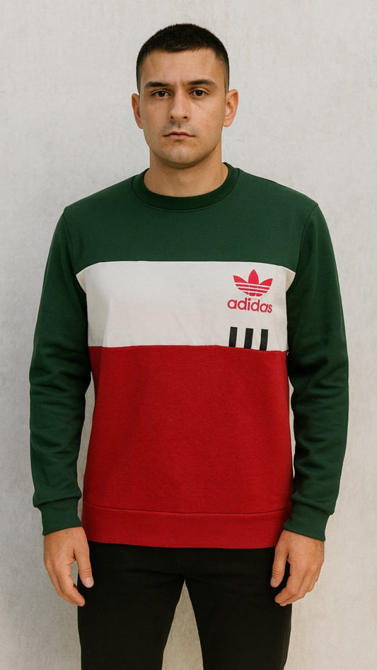 Person wearing a green, white, and red Adidas sweatshirt against a plain background