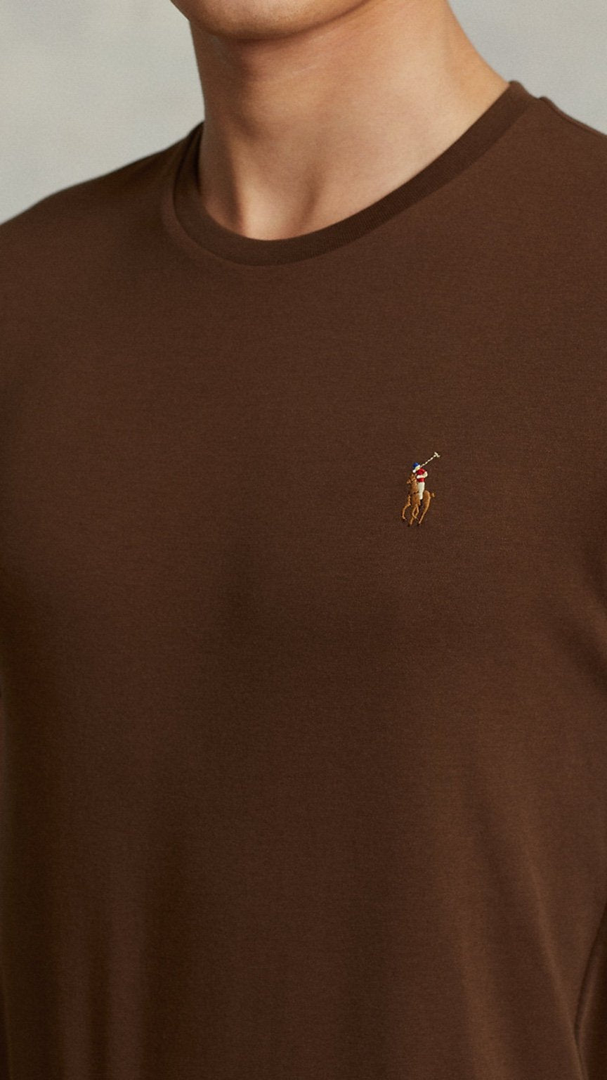 Brown t-shirt with a small logo on a neutral background