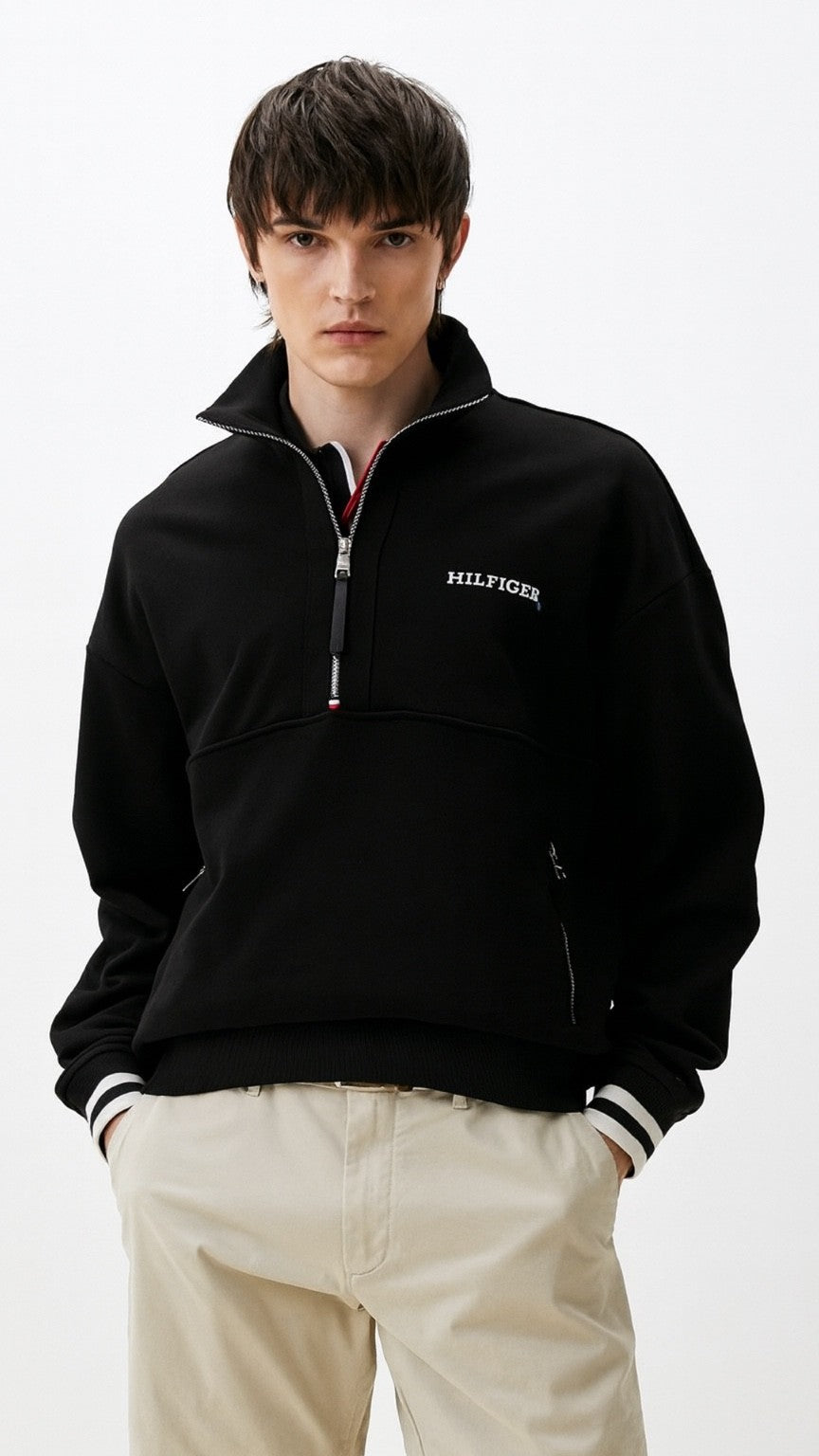 Person wearing a black Tommy Hilfiger pullover on a white background
