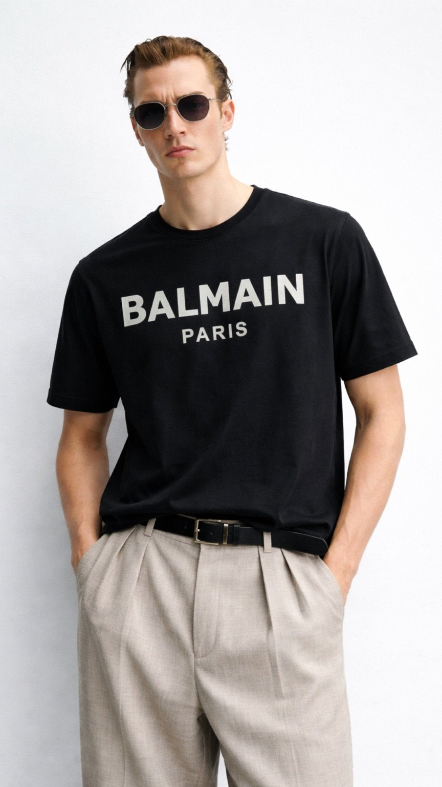 Man wearing a black Balmain Paris t-shirt against a white background