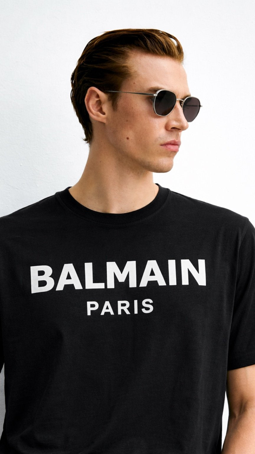 Man wearing a black Balmain Paris t-shirt against a white background