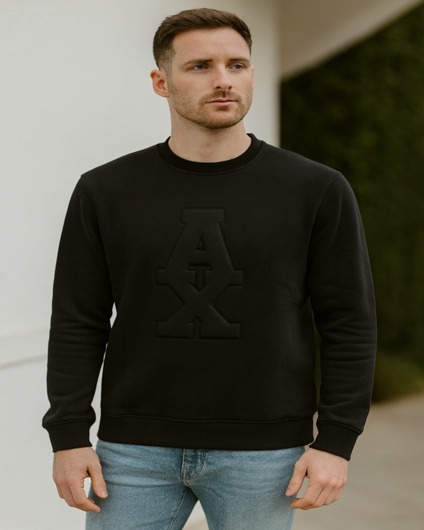 Man wearing a black sweatshirt with a large letter 'A' on a neutral background