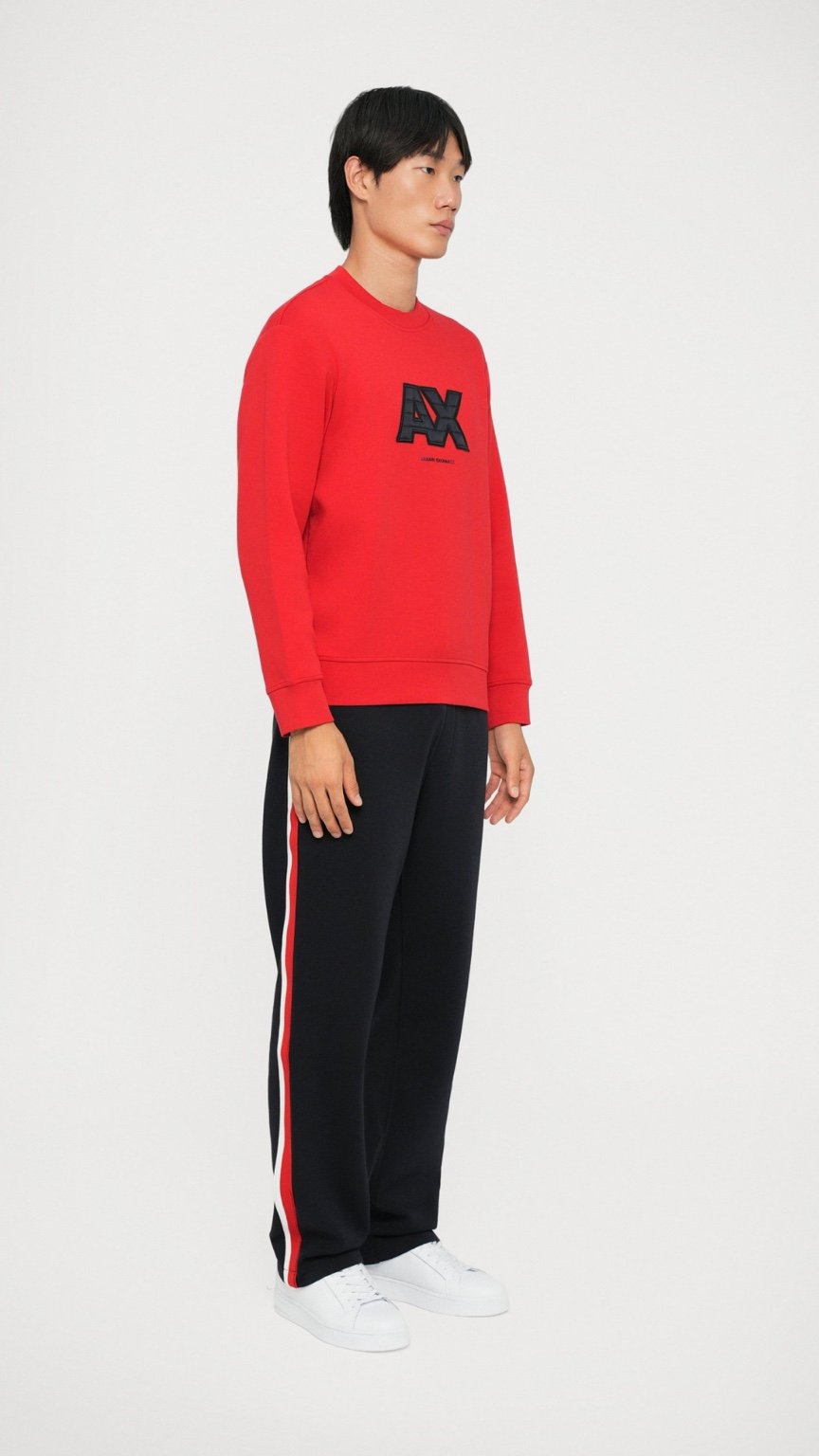 Person wearing a red sweatshirt with a logo and black pants on a white background
