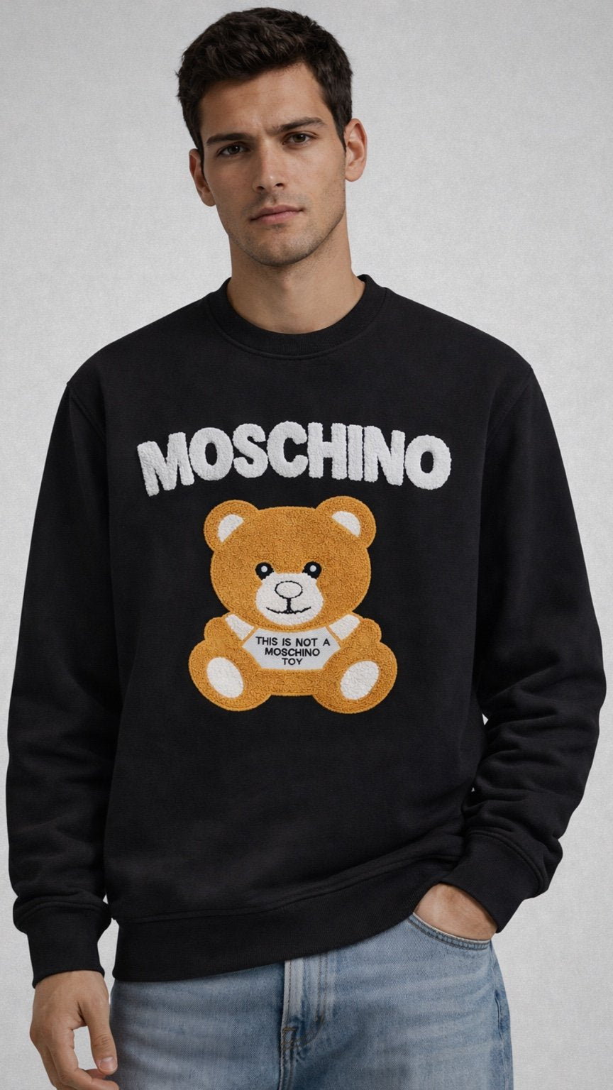 Man wearing a black Moschino sweatshirt with a bear graphic on a gray background
