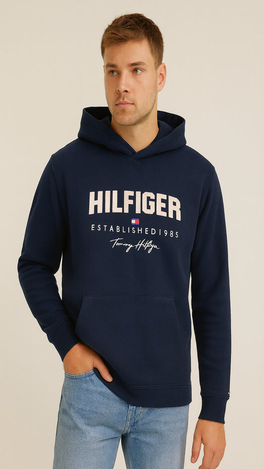 Man wearing a navy Tommy Hilfiger hoodie on a beige background