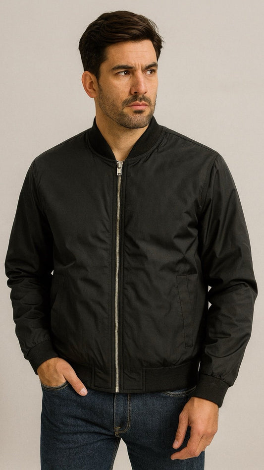 Man wearing a black bomber jacket against a neutral background