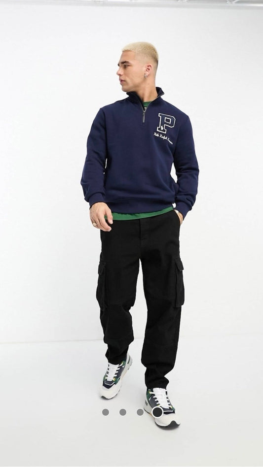 Man wearing a navy blue sweatshirt with a logo and black pants on a white background