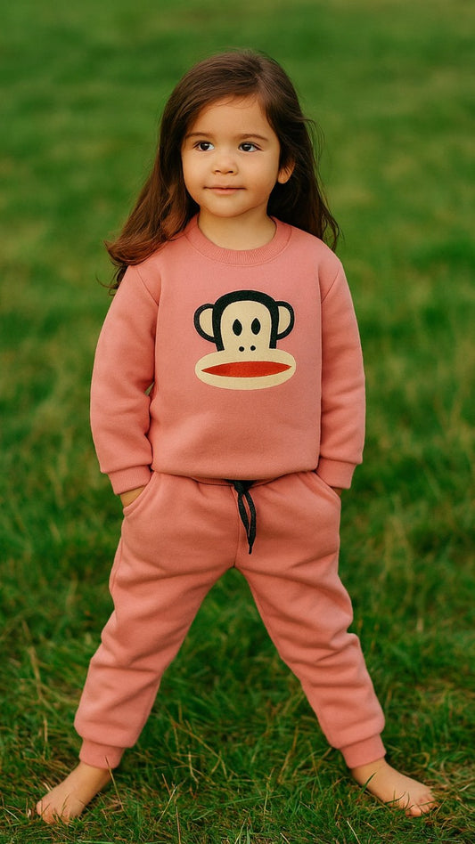 Child wearing a pink outfit with a cartoon character on a grassy background