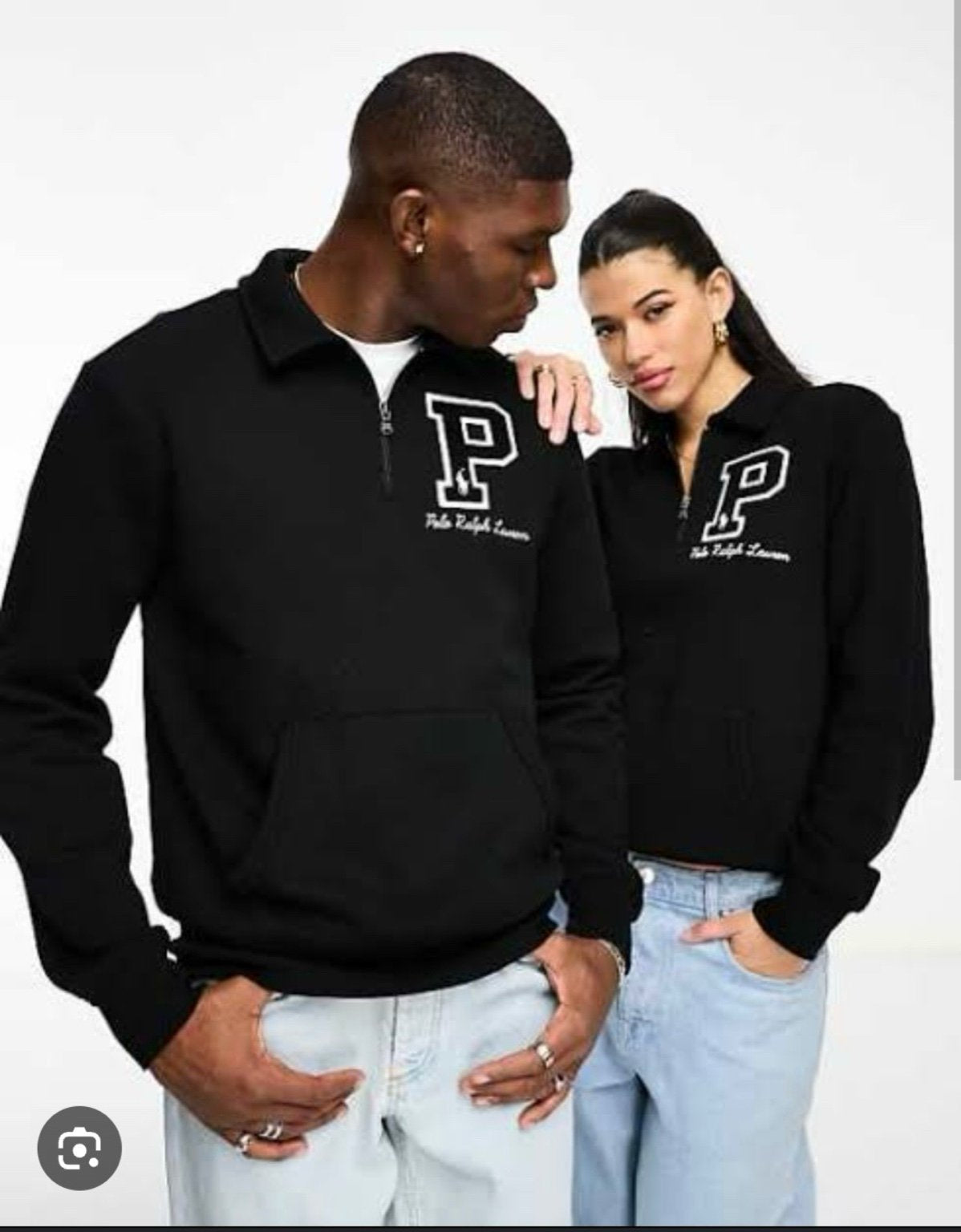 Two people wearing black polo shirts with a logo on a white background