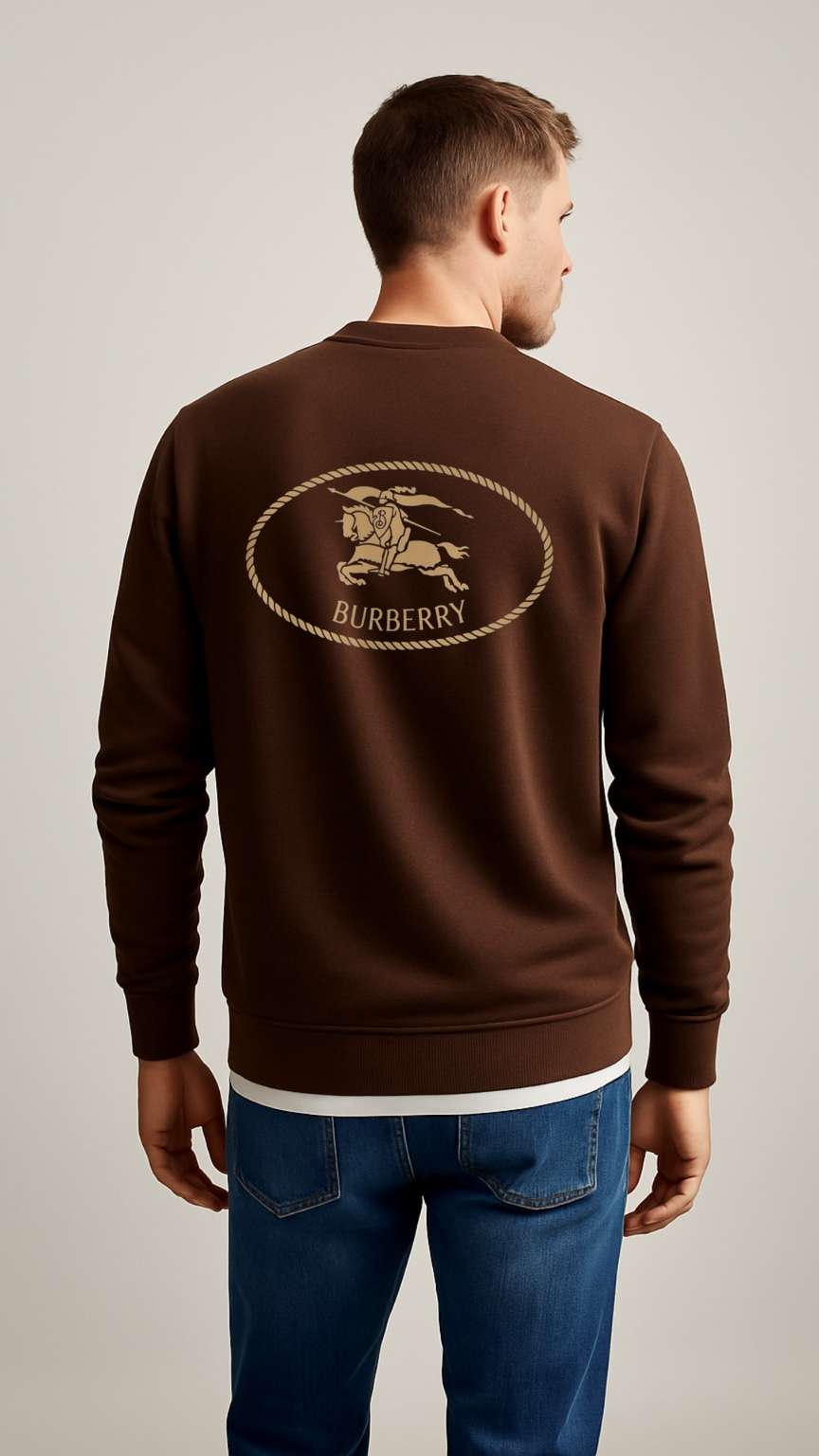 Man wearing a brown Burberry sweatshirt with a lion emblem on a plain background