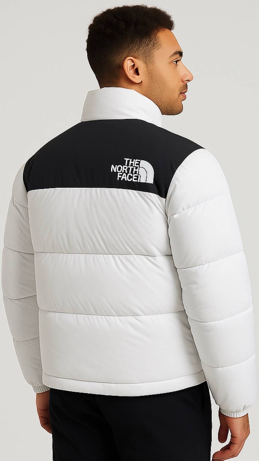 Person wearing a white The North Face jacket with black logo on a light gray background